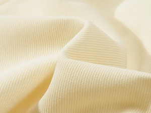 Macro shot of soft creamy white heavy knit fabric texture with fine vertical ribbed details