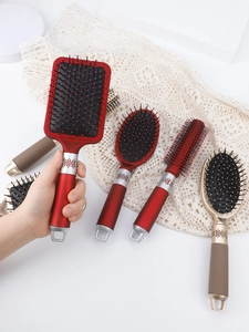 Close-up of wine red paddle and round hairbrush set with gold ring detail on lace