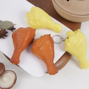 Realistic PVC chicken drumstick keychain models in brown and yellow on a white plate