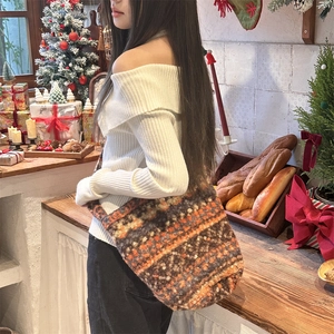 Detail of the cozy knit bucket bag featuring a retro mixed-color pattern on a model