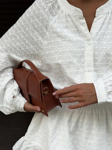 Gros plan détaillé sur la broderie cœur et le sac à main géométrique en cuir marron