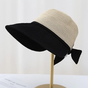 Detail of a straw sun hat with black bubble fabric brim and decorative bow on gold stand