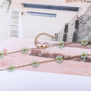 Detail of gold chain bracelet with light green crystal flower charms and lobster clasp