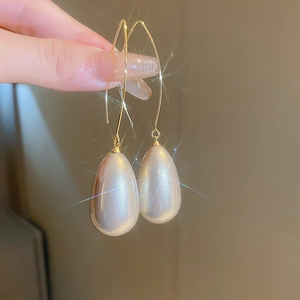 Gros plan de boucles d'oreilles dorées avec perles blanches en forme de goutte d'eau