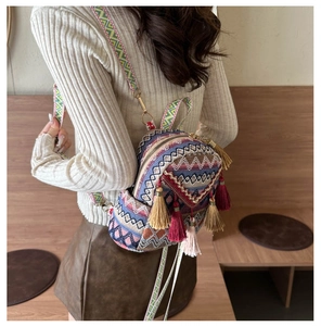 Detailed view of woven fabric backpack featuring geometric patterns and fringe tassels