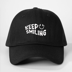 Detailed close-up of KEEP SMILING embroidery on a black cotton baseball cap