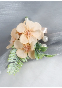Detail of peach faux hydrangea corsage with green leaves, pearls, and champagne ribbon