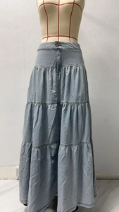 Dettaglio gonna lunga in denim azzurro a tre strati con balze e chiusura con bottoni