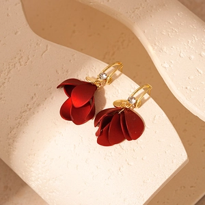 Macro detail of red petal earrings with gold hooks and sparkling zircon accents