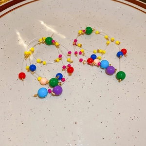 Close-up of vibrant multicolored resin beaded hoop earrings in a ceramic tray