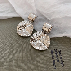 Detail of silver geometric earrings with hammered texture and polished square studs