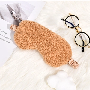 Close-up of cozy brown teddy fleece sleep mask with elastic silk strap on plush background
