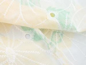 Dettaglio macro del tessuto in cotone bianco con ricamo floreale e design traforato