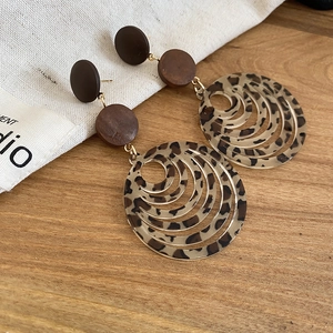 Macro view of leopard print resin earrings with wood texture rings and golden metal studs