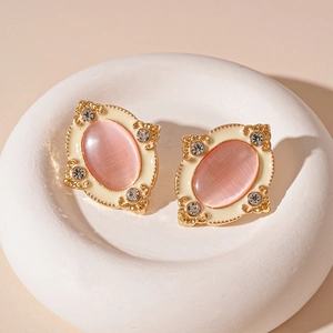 Macro detail of vintage oval earrings with pink cat eye stone and crystal accents