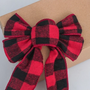 Close-up of red and black plaid decorative ribbon bow on a kraft paper gift box