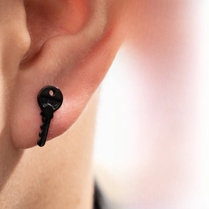 Detail view of a black key-shaped stainless steel stud earring for a punk look