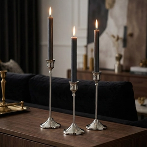 Juego de tres candelabros de metal plateado con velas grises para decoración moderna