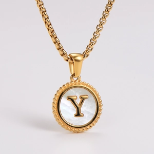 Detailed view of golden pendant necklace with white shell inlay and letter Y engraving
