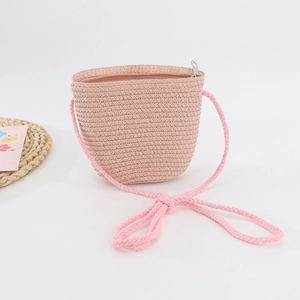 Vista dettagliata della borsa di paglia rosa intrecciata a mano per bambini con tracolla