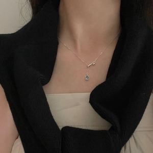 Close-up of S925 sterling silver necklace with a blue teardrop pendant on a model
