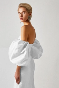 Detail of elegant white off-shoulder dress featuring voluminous puff sleeves and slim fit