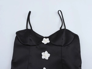 Detail view of black satin strap dress featuring white floral 3D appliqués with pearls