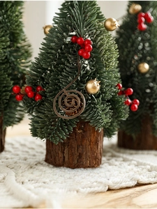 Detailed view of mini snowy Christmas tree with red berries on a rustic wooden base