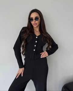 Detailed view of women's black ribbed knit suit featuring a V-neck cardigan and slim pants
