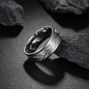 Macro shot of 8mm brushed stainless steel ring with V-shaped patterns on dark stone