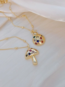 Detailed close-up of gold plated mushroom and ladybug pendants with colorful zircon gems
