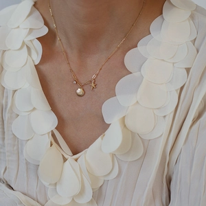 Maldives style gold shell and starfish pendant necklace with cubic zirconia on model