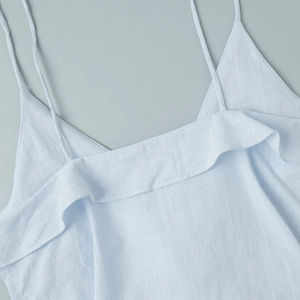 Detailed view of light blue cotton camisole top with thin straps and ruffle neckline