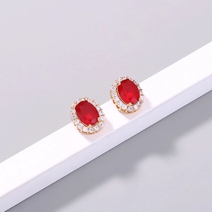 Detail shot of golden clover stud earrings with oval red zircon and white halo crystals