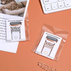 Close-up of diamond silicone watch strap charms with heart and paw prints in packaging