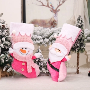 Pink plush Christmas stockings with knit Santa and snowman figurines for holiday decor