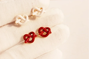 Dettaglio macro di orecchini a nodo di cuore in smalto rosso e bianco su tessuto