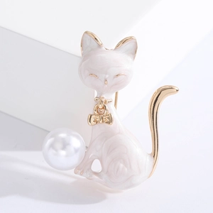 Detailed close-up of a white enamel cat brooch with gold plating and a round pearl inlay