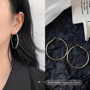 Detail shot of 5cm large gold hoop earrings showing fine brushed texture and scale on model