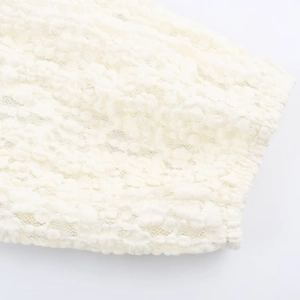 Detailed macro view of off-white floral lace fabric and delicate crochet on the sleeve