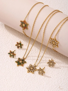 Detail von goldenem Schneeflocken-Schmuckset mit bunten Zirkonsteinen auf Rosa Display