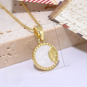 Macro view of gold plated round sunburst necklace with white shell inlay and scallop texture