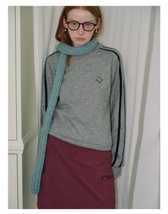 Detailed texture of a light blue chunky knit scarf paired with a vintage style outfit