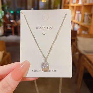 Dettaglio della collana con pendente quadrato e zircone su cartoncino bianco