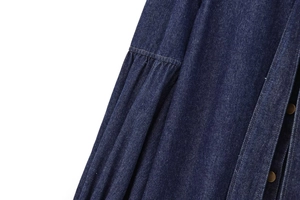 Detail of dark blue denim shirt showing pleated design and metal buttons texture