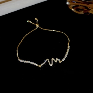 Macro shot of gold heartbeat slider bracelet with zircons and adjustable bolo clasp