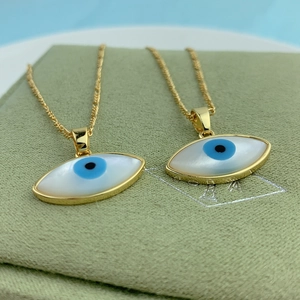 Macro view of gold evil eye necklace with white mother of pearl on green velvet