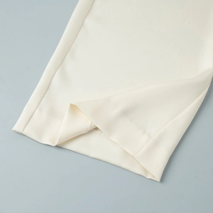 Detail view of smooth ivory satin trousers hem with high-quality stitching and drape