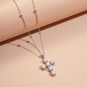 Close-up of silver cross pendant featuring white pearls and shimmering zircon accents