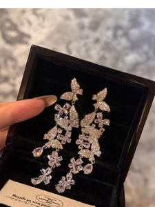 Macro detail of silver drop earrings with butterfly fringe and sparkling zircons